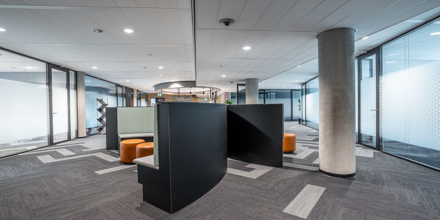 Completed contemporary office interior with glass walls, meeting booths, and concrete columns