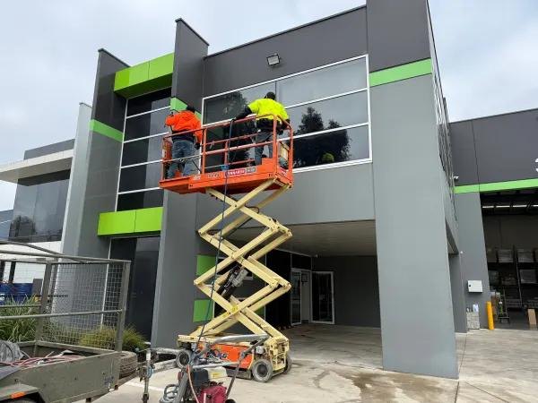 Construction workers on a scissor lift working on a commercial building exterior