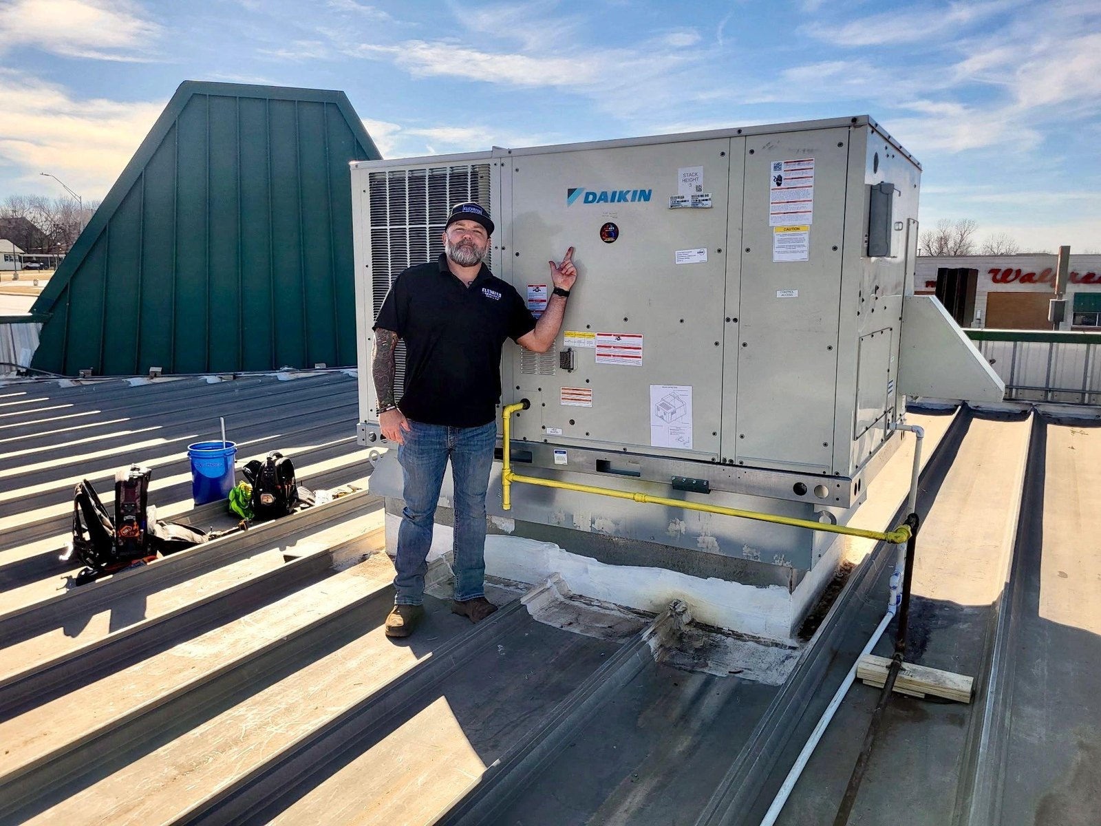 Technician beside a rooftop commercial HVAC unit